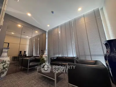 Modern living room with sleek black leather sofas and floor-to-ceiling windows with blinds.
