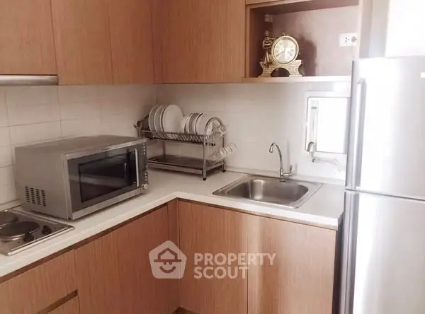 Modern kitchen with wooden cabinets, stainless steel appliances, and compact design.