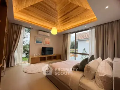 Luxurious bedroom with wooden ceiling and large windows offering serene garden views.