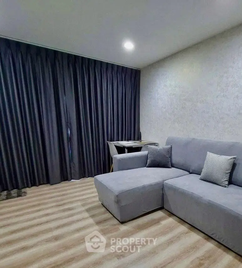 Modern living room with sleek gray sofa and elegant curtains, perfect for cozy relaxation.