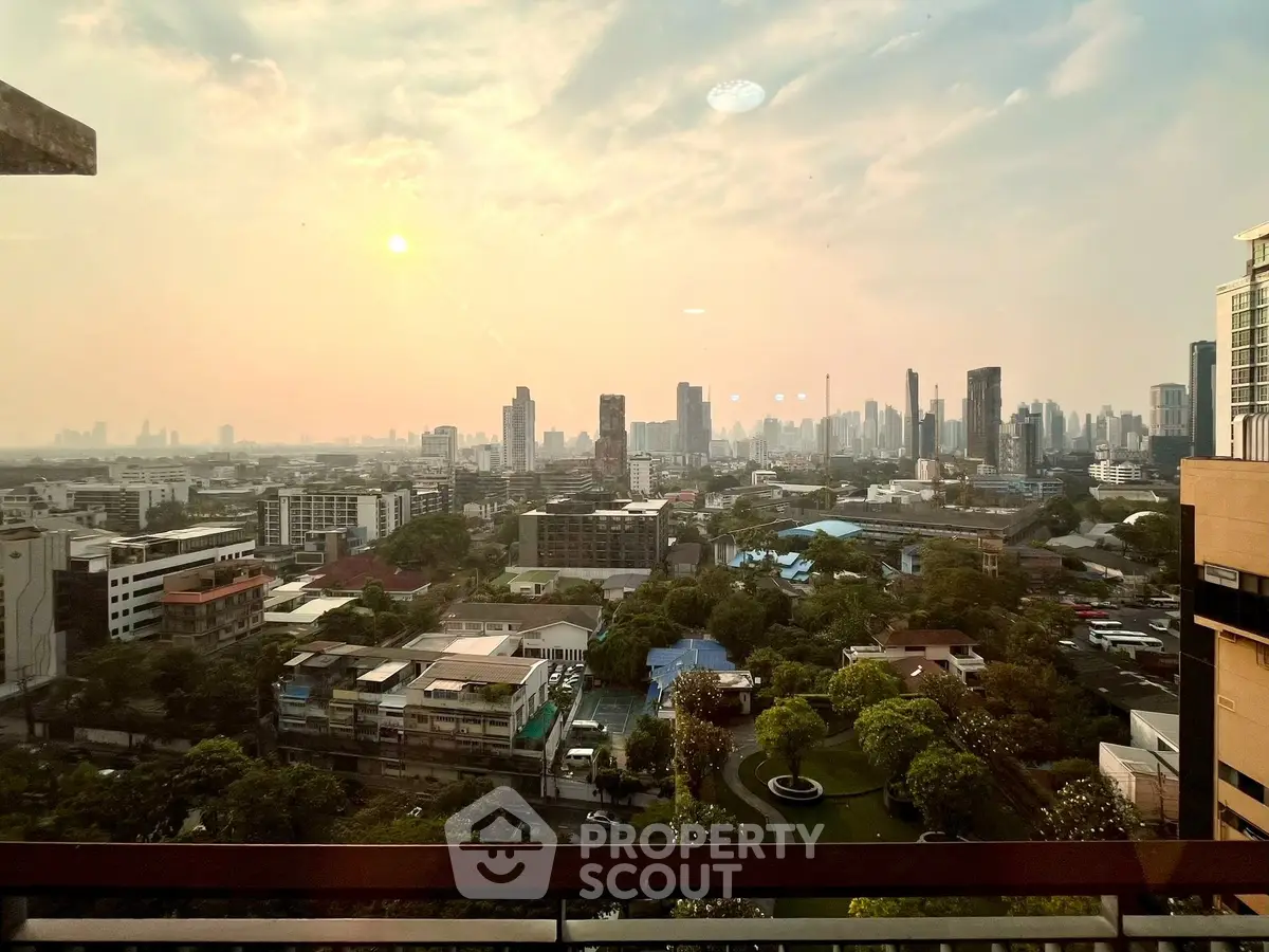 Stunning cityscape view from a high-rise balcony at sunset, showcasing urban skyline and lush greenery.