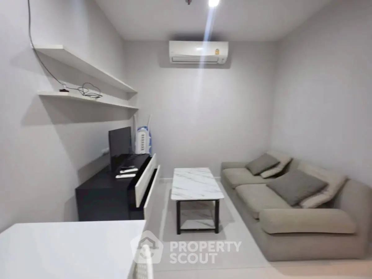 Cozy living room with modern sofa, TV, and air conditioning in a stylish apartment.
