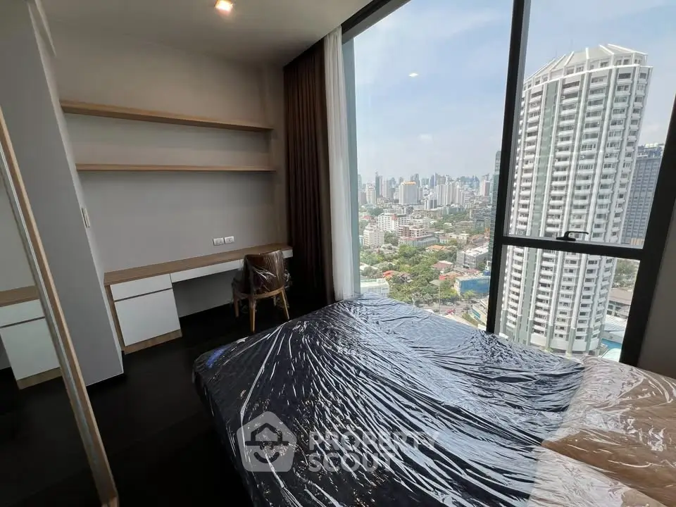 Modern bedroom with city view, featuring sleek furniture and large windows for natural light.