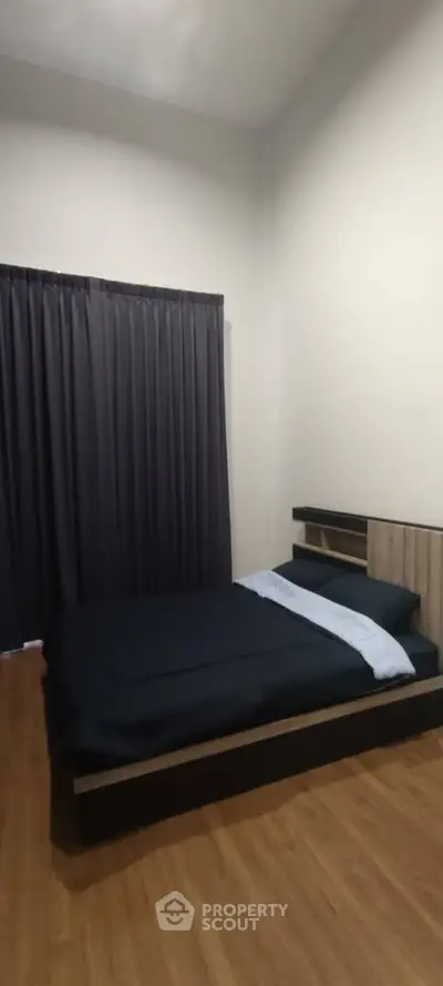 Cozy bedroom with modern design and wooden flooring, featuring a comfortable bed and elegant curtains.