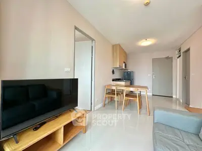 Modern living room with open kitchen, sleek furniture, and natural light.