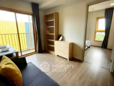 Modern apartment with open living room and bedroom, featuring wooden flooring and natural light.