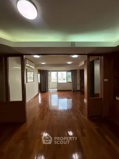 Spacious living room with wooden flooring and city view, perfect for modern living.