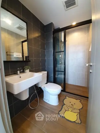 Modern bathroom with sleek black tiles and glass shower enclosure.