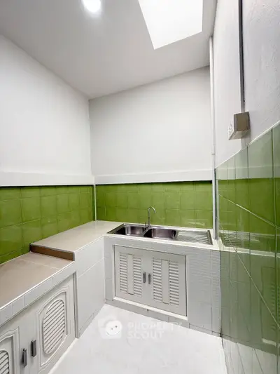 Charming kitchen with green tile backsplash and dual sink, perfect for culinary enthusiasts.