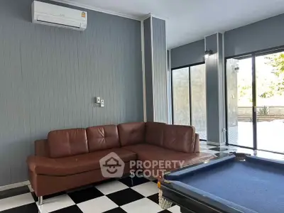 Stylish living room with leather sofa and pool table, perfect for entertainment.