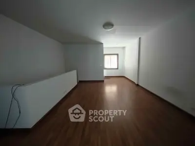 Spacious empty living room with wooden flooring and natural light.