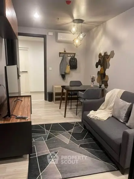 Modern living room with stylish decor and geometric rug in cozy apartment.