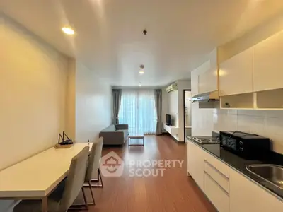 Modern open-layout living room and kitchen with sleek furniture and natural light.