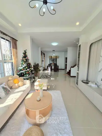 Spacious living room with modern decor and Christmas tree, perfect for family gatherings.