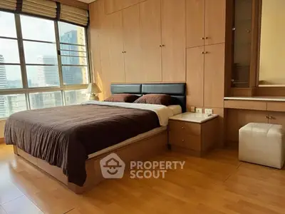 Spacious bedroom with city view, featuring wooden flooring and built-in storage.