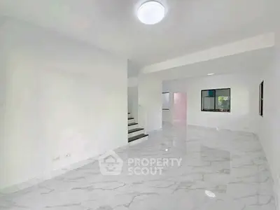 Spacious modern living room with marble flooring and ample natural light.