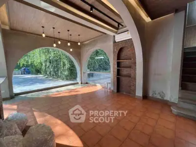 Spacious interior with large arched windows and terracotta flooring, perfect for a bright living space.
