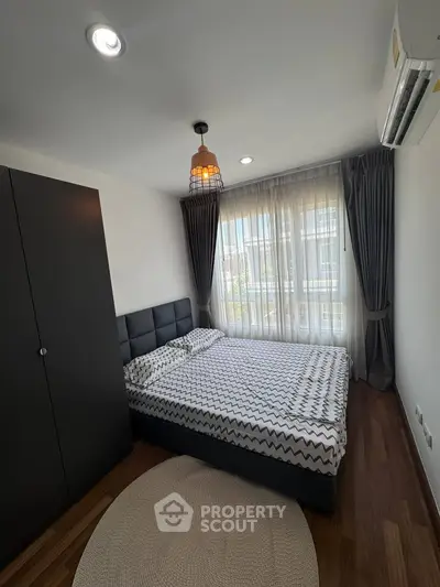 Modern bedroom with stylish decor and large window offering natural light