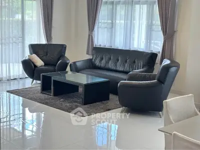Stylish living room with modern black leather furniture and large windows.