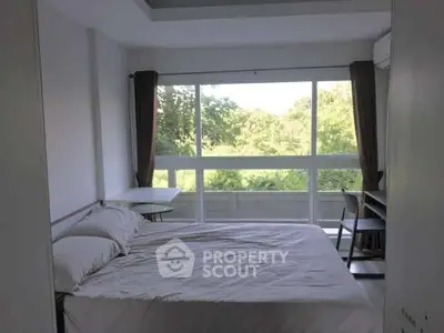 Bright bedroom with large window and serene green view