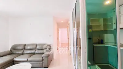 Modern living room with sleek leather sofa and compact kitchen in open layout.