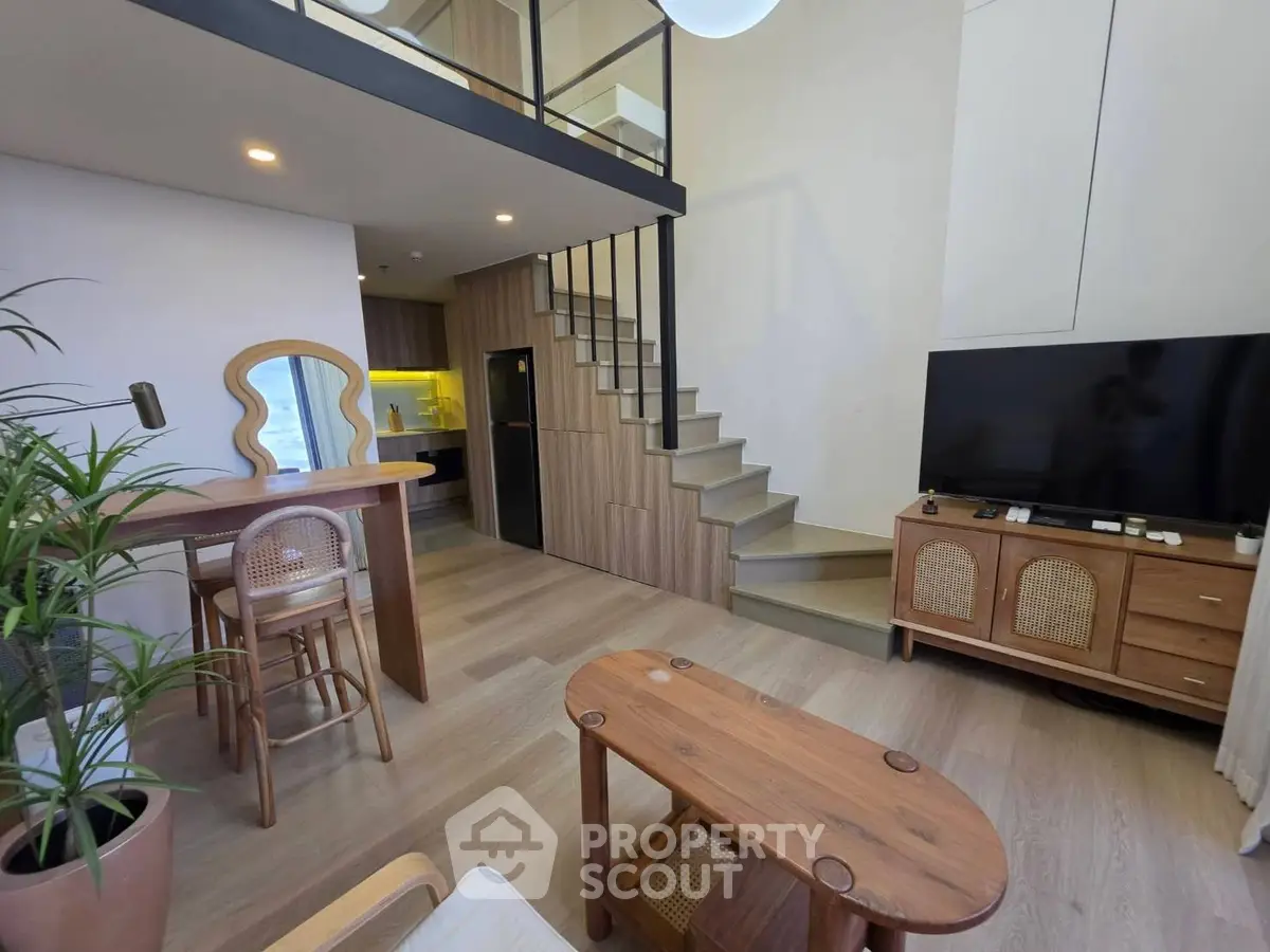 Modern loft-style living room with mezzanine, stylish furniture, and open kitchen layout.