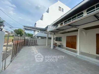 Spacious outdoor area with tiled flooring and covered parking in a modern residential property.