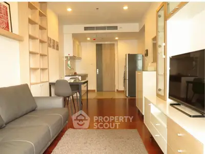 Modern living room with open kitchen, sleek furniture, and warm lighting.