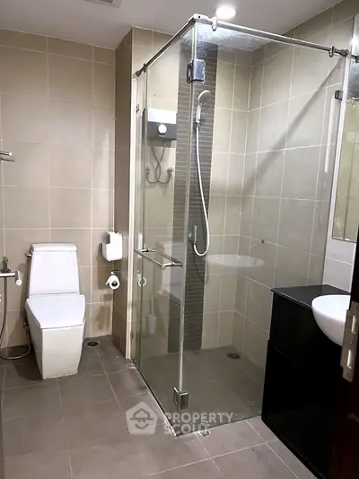 Modern bathroom with glass shower enclosure and sleek fixtures in a contemporary apartment.