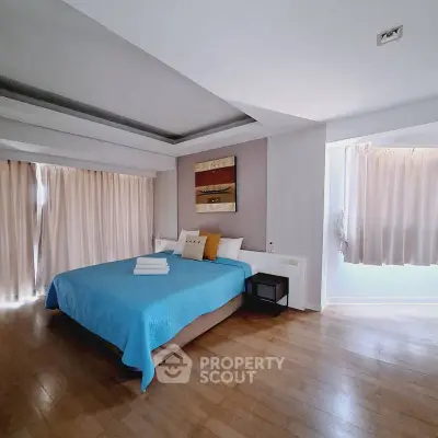 Spacious bedroom with modern decor and natural light, featuring a cozy bed and elegant wooden flooring.