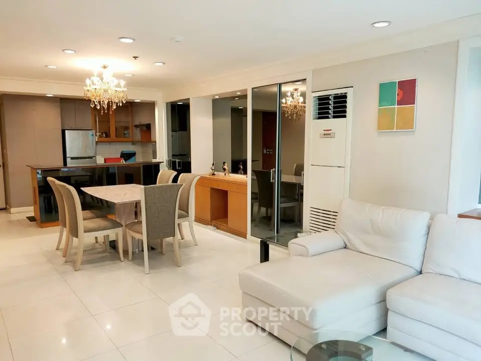 Spacious open-plan living and dining area with modern kitchen and elegant chandelier.