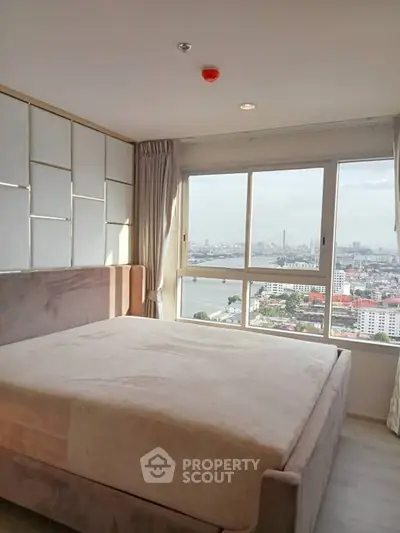 Spacious bedroom with stunning city view and large window in modern apartment.