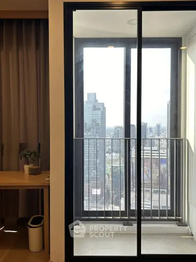 Modern apartment balcony with stunning city view through glass doors.