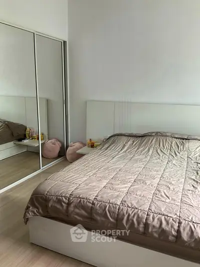 Cozy bedroom with mirrored closet and modern decor, perfect for relaxation.
