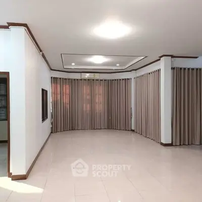 Spacious living room with elegant curtains and recessed lighting, perfect for modern living.