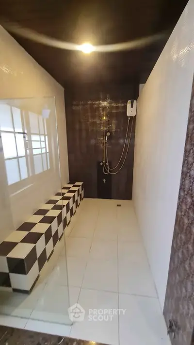 Modern bathroom with sleek design and checkered bench, featuring a glass shower enclosure and stylish fixtures.
