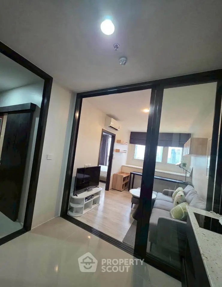 Modern living room with glass partition and cozy seating area in a stylish apartment.