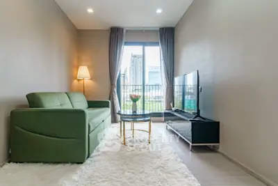Modern living room with green sofa, large window, and city view, perfect for urban living.