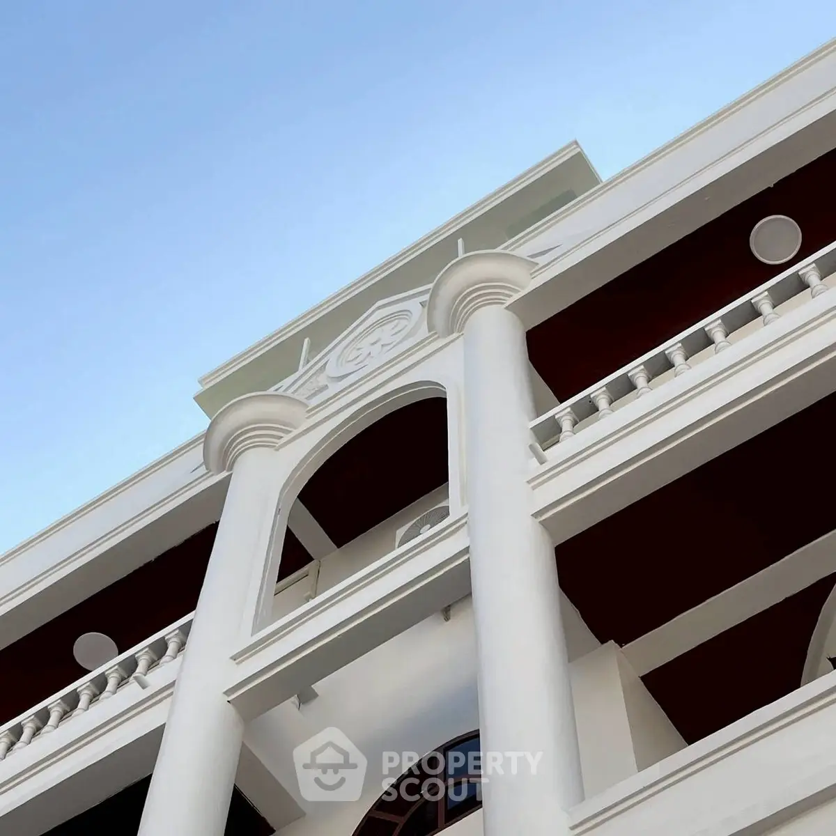 Elegant architectural facade with classic columns and balconies under clear blue sky.