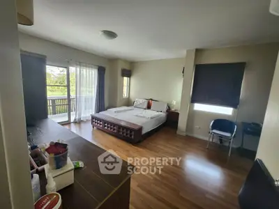 Spacious bedroom with balcony and wooden flooring in modern apartment