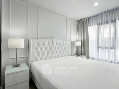 Luxurious bedroom with elegant white decor and plush headboard, featuring ample natural light through large windows.