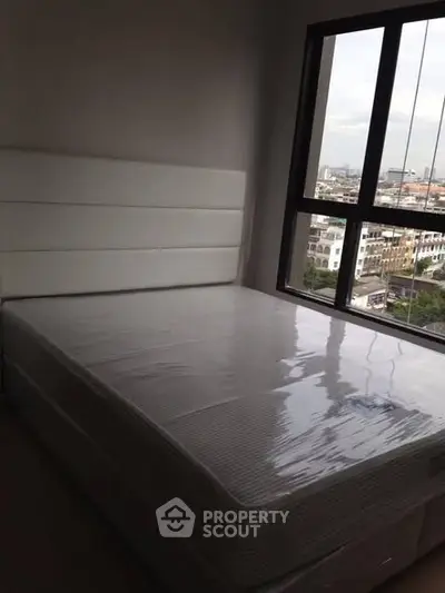 Modern bedroom with large window offering city view and natural light.