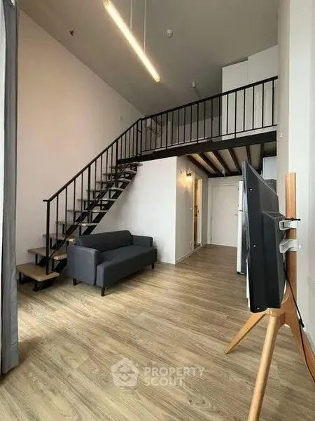 Modern loft apartment with mezzanine, stylish staircase, and sleek wooden flooring.