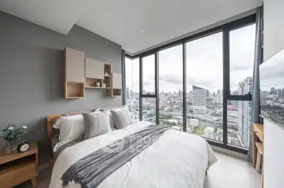 Modern bedroom with stunning city view through floor-to-ceiling windows, featuring stylish decor and cozy bedding.