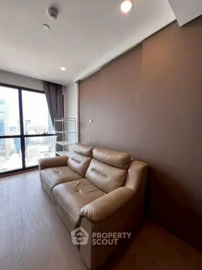 Modern living room with leather sofa and city view through large window.