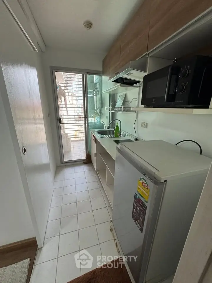 Compact kitchen with modern appliances and balcony access in urban apartment