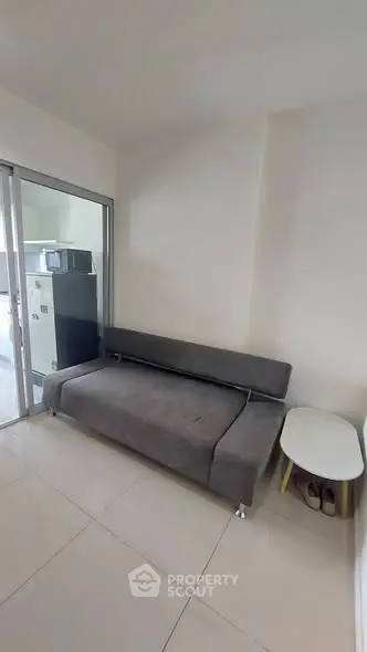 Modern living room with sleek gray sofa and glass partition, perfect for urban living.