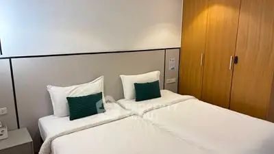 Modern bedroom with twin beds and wooden wardrobe, ideal for cozy living.