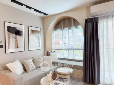 Modern living room with stylish decor and large arched window, featuring cozy seating and contemporary artwork.