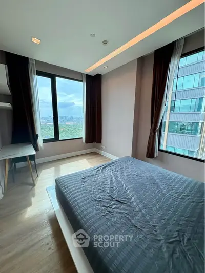 Modern bedroom with large windows offering stunning city views in a high-rise apartment.